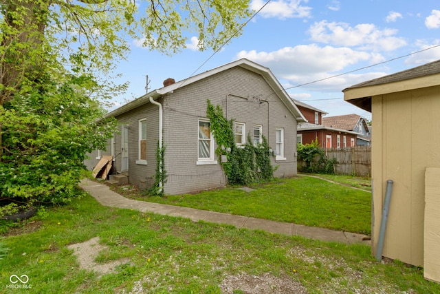 view of property exterior with a yard, fence, and entry steps