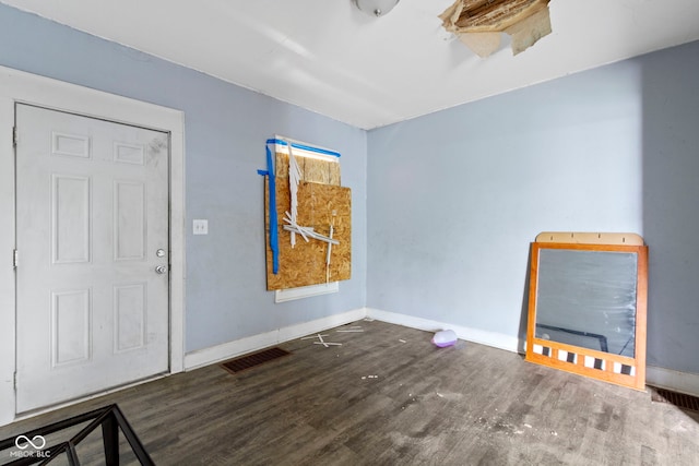 empty room featuring baseboards, visible vents, and wood finished floors
