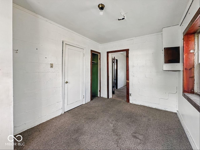 carpeted spare room with concrete block wall
