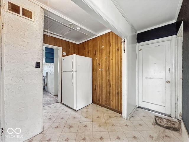 kitchen featuring crown molding, wooden walls, visible vents, freestanding refrigerator, and light floors
