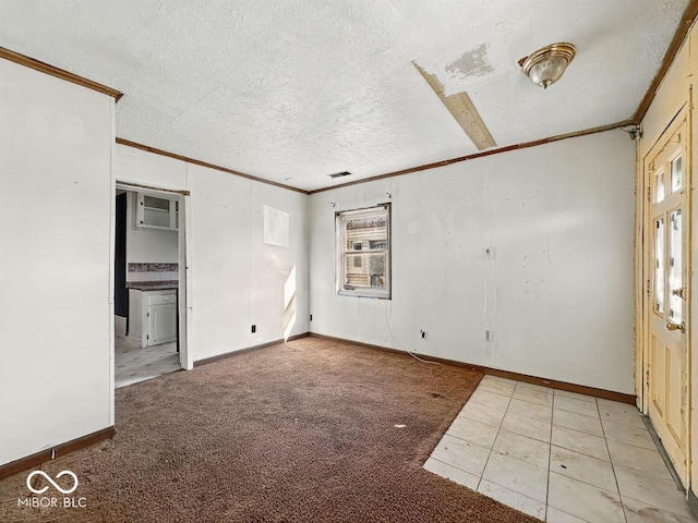 unfurnished room featuring a textured ceiling, baseboards, visible vents, ornamental molding, and carpet