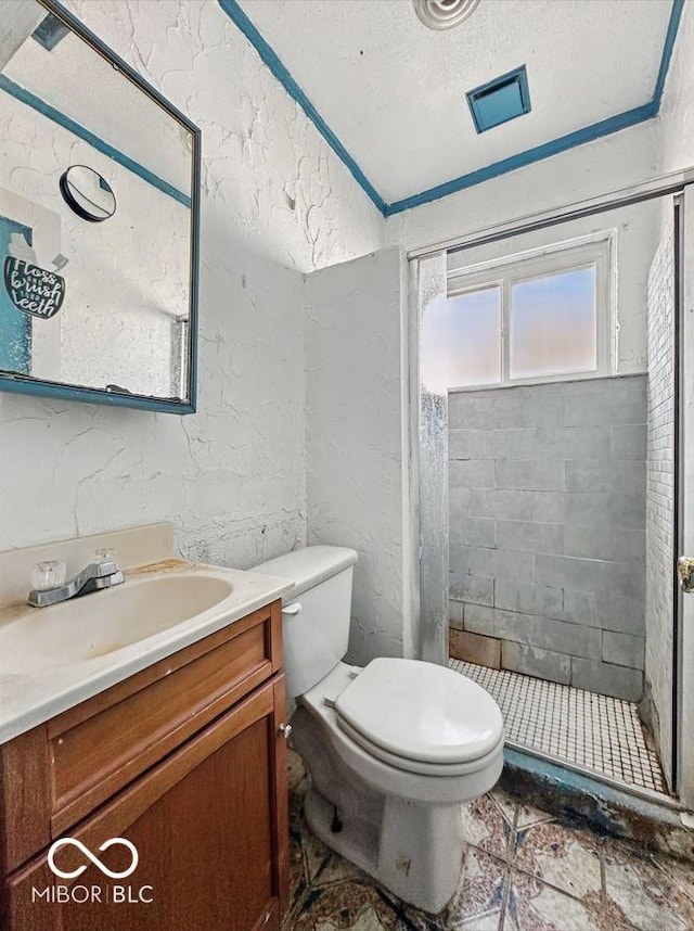 full bathroom featuring a textured ceiling, toilet, vanity, a stall shower, and a textured wall