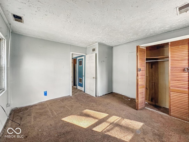 unfurnished bedroom with visible vents, a closet, carpet flooring, and a textured ceiling