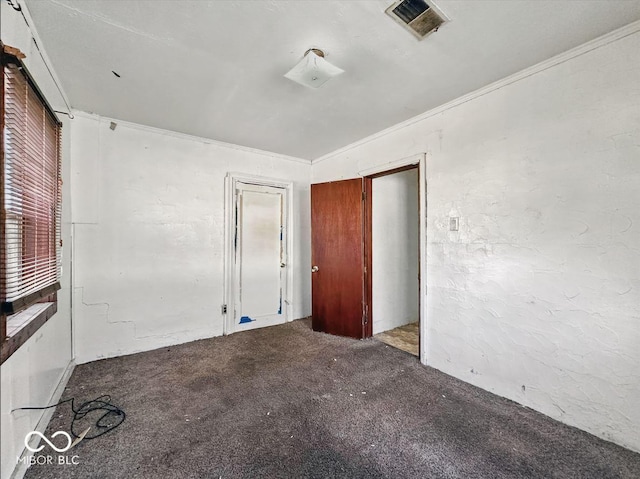 unfurnished bedroom with a textured wall, carpet floors, visible vents, and crown molding