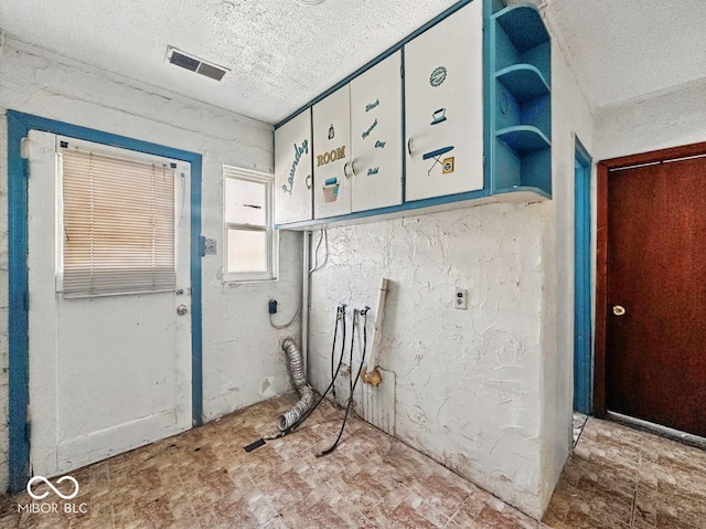 interior space with a textured wall, a textured ceiling, and visible vents