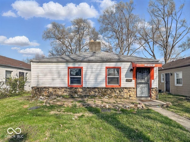 view of front of house featuring stone siding, a chimney, and a front lawn