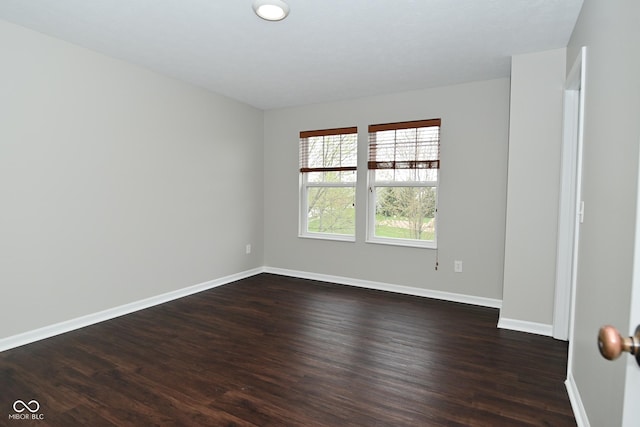 empty room featuring baseboards and dark wood finished floors