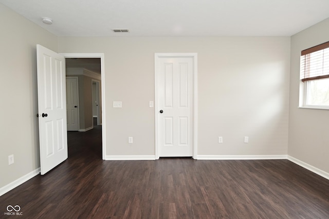 unfurnished bedroom featuring dark wood-type flooring, visible vents, and baseboards