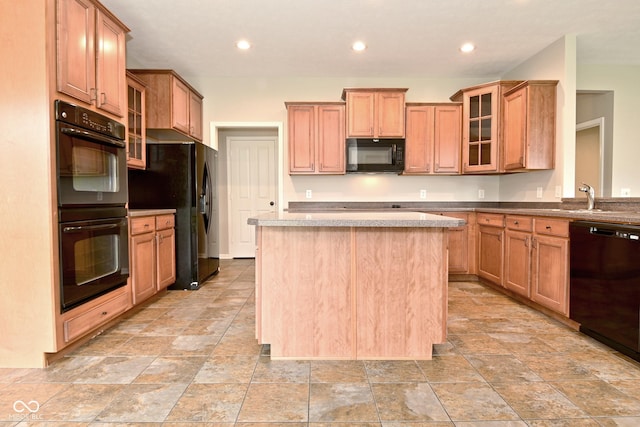 kitchen featuring recessed lighting, stone finish floor, a center island, black appliances, and glass insert cabinets