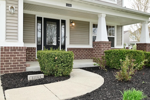 property entrance featuring brick siding and a porch