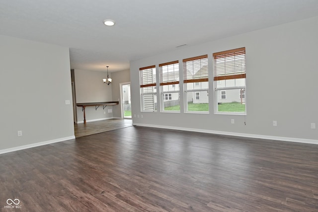 unfurnished living room featuring a healthy amount of sunlight, baseboards, and a notable chandelier