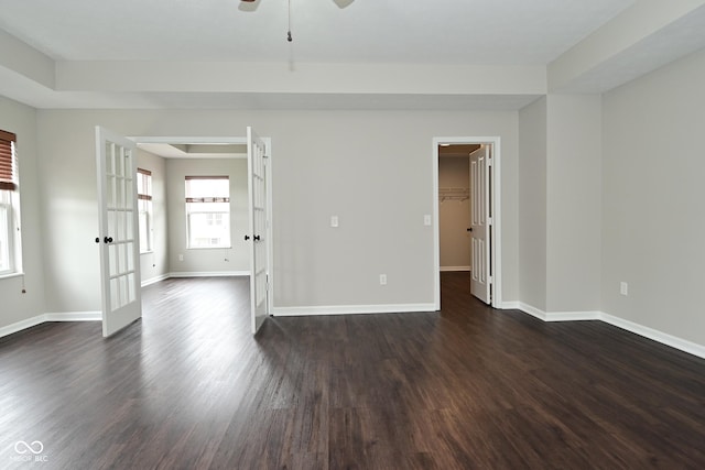 empty room featuring a ceiling fan, baseboards, and dark wood finished floors