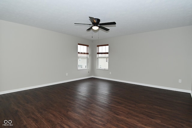 empty room featuring baseboards, ceiling fan, and dark wood finished floors
