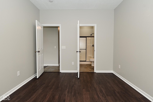 unfurnished bedroom featuring wood finished floors, baseboards, and connected bathroom