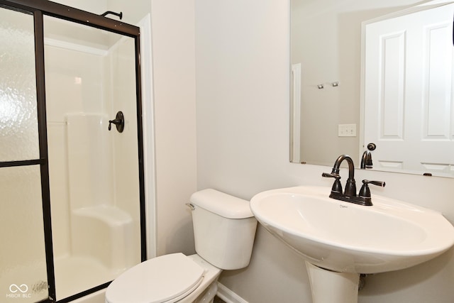 bathroom featuring a shower stall, toilet, and a sink