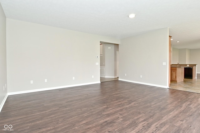 unfurnished room featuring baseboards, recessed lighting, a sink, and dark wood finished floors