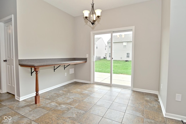 unfurnished dining area with an inviting chandelier, stone finish floor, and baseboards