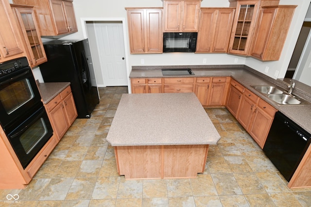 kitchen with a sink, black appliances, glass insert cabinets, stone finish floor, and a kitchen island