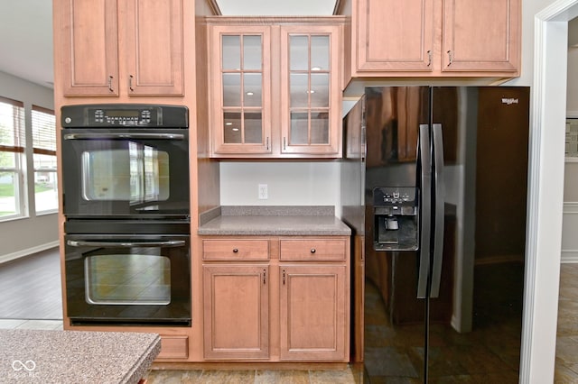 kitchen with black appliances, baseboards, and glass insert cabinets