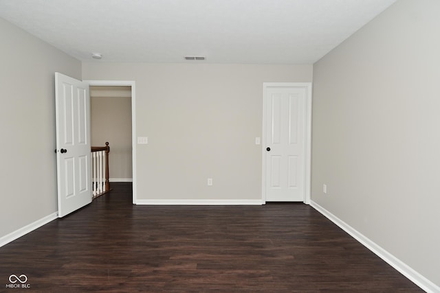 unfurnished room featuring baseboards, visible vents, and dark wood-type flooring