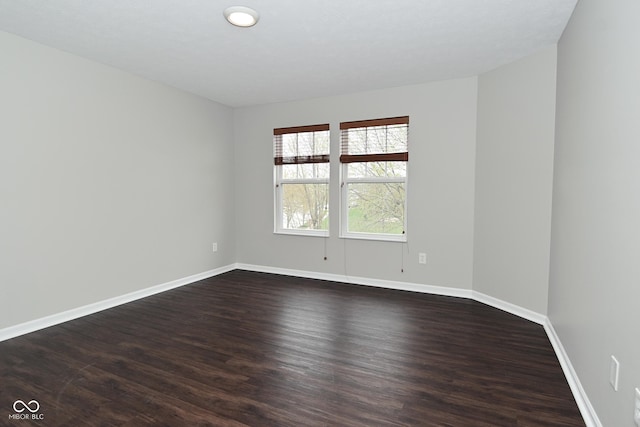 unfurnished room featuring dark wood-type flooring and baseboards