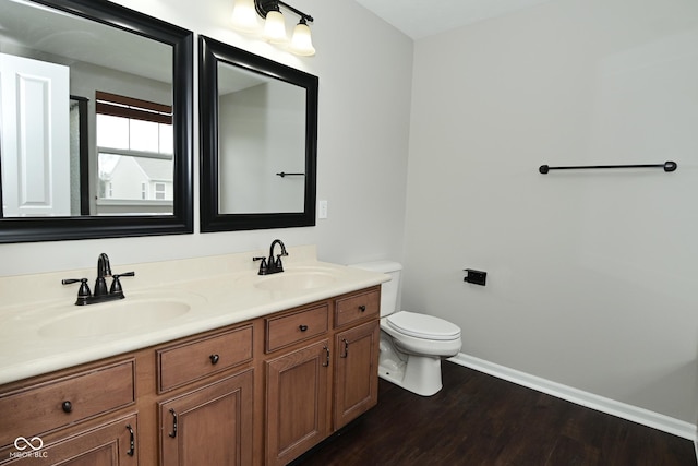 bathroom featuring baseboards, wood finished floors, a sink, and toilet