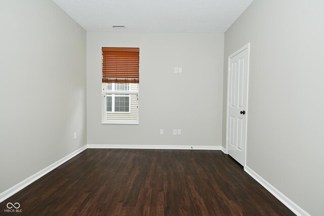 spare room with visible vents, baseboards, and dark wood-style flooring