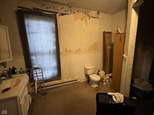 bathroom featuring a wainscoted wall, toilet, vanity, concrete floors, and baseboard heating