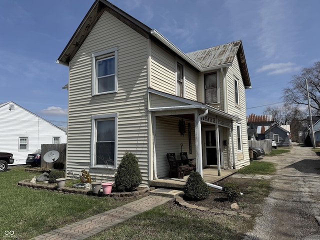 traditional home featuring a front lawn, metal roof, and covered porch