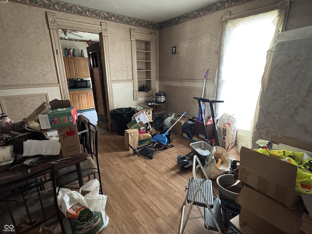 interior space with a wainscoted wall, wallpapered walls, and wood finished floors