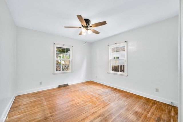 spare room featuring visible vents, ceiling fan, light wood-style floors, and baseboards