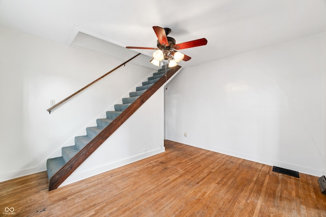 unfurnished living room featuring wood-type flooring, ceiling fan, and stairway