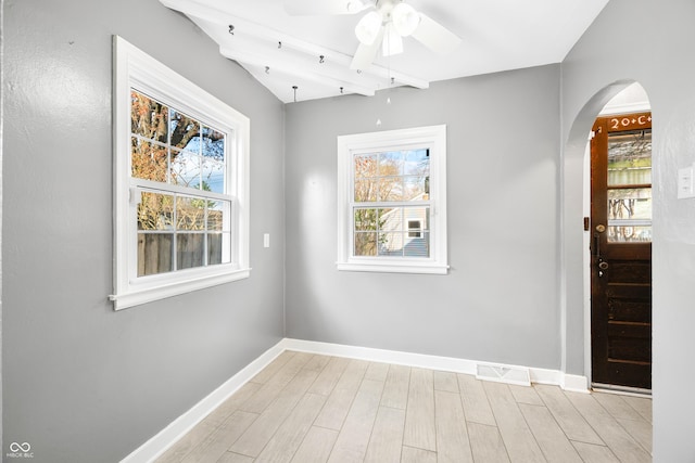 spare room featuring visible vents, a wealth of natural light, arched walkways, and baseboards