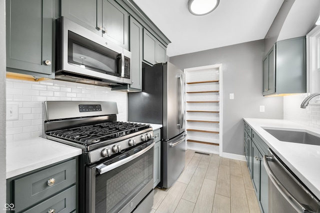 kitchen with tasteful backsplash, baseboards, a sink, appliances with stainless steel finishes, and wood tiled floor