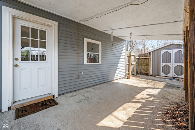 view of patio with fence, an outbuilding, and a storage unit