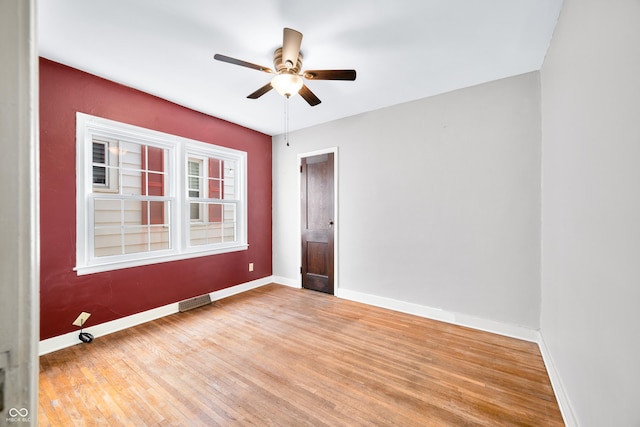 unfurnished room featuring visible vents, baseboards, a ceiling fan, and wood finished floors