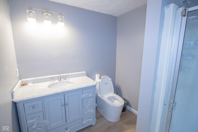 bathroom with toilet, vanity, a textured ceiling, and wood finished floors