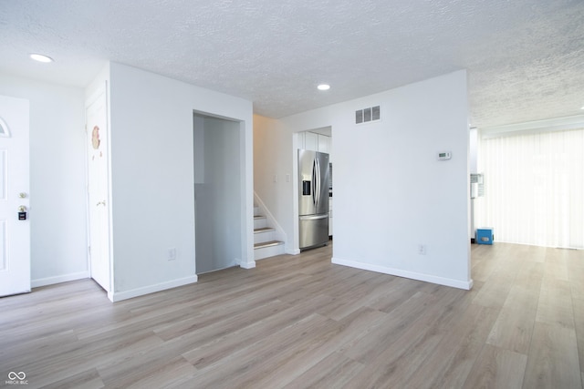 unfurnished living room with a textured ceiling, stairway, visible vents, recessed lighting, and light wood finished floors