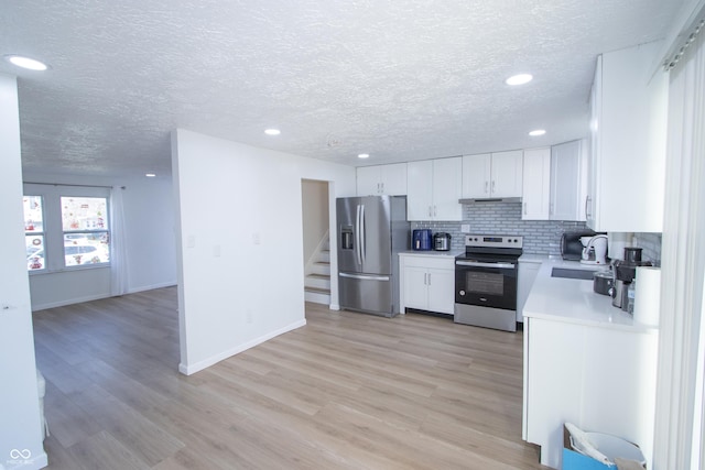 kitchen featuring a sink, stainless steel appliances, backsplash, light countertops, and a textured ceiling