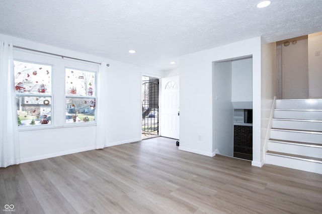 unfurnished living room with recessed lighting, wood finished floors, and a textured ceiling