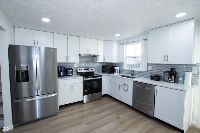 kitchen featuring stainless steel appliances, a textured ceiling, light countertops, and a sink