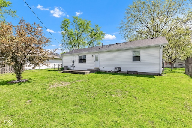 rear view of house with a lawn and a fenced backyard