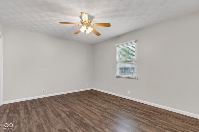 spare room with dark wood-type flooring, a ceiling fan, baseboards, and visible vents