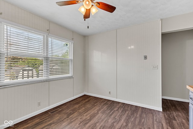 unfurnished room featuring baseboards, a ceiling fan, wood finished floors, and visible vents