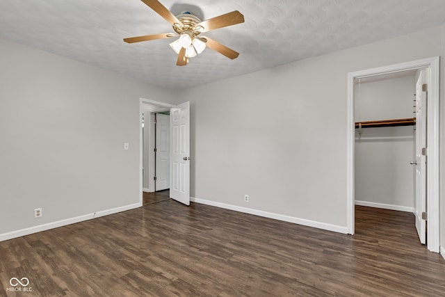 unfurnished bedroom with a walk in closet, baseboards, wood finished floors, and a closet