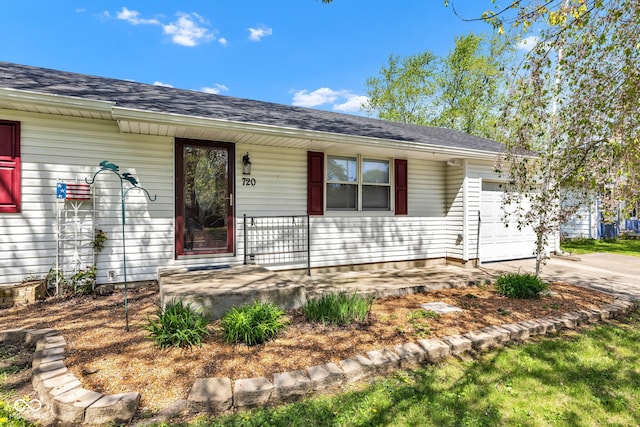 ranch-style house featuring concrete driveway, an attached garage, a shingled roof, and covered porch