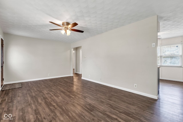 unfurnished living room featuring baseboards, a ceiling fan, and dark wood finished floors
