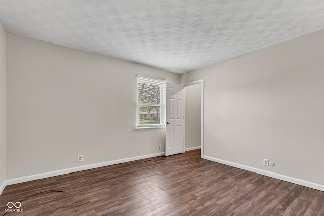 unfurnished room with a textured ceiling, baseboards, and dark wood-type flooring
