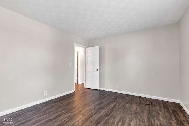 unfurnished room featuring baseboards and dark wood-style floors