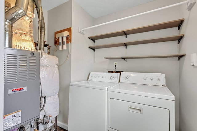 clothes washing area featuring laundry area, washer and clothes dryer, and heating unit